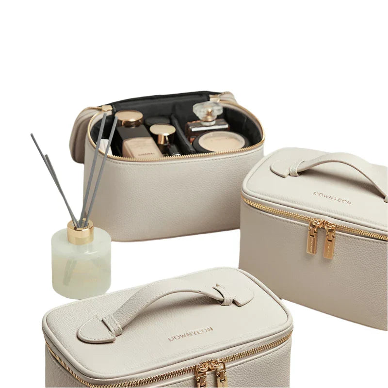 Set di eleganti beauty case in pelle beige con cerniera dorata, ideali per cosmetici e accessori da viaggio. Include diffusore profumato.