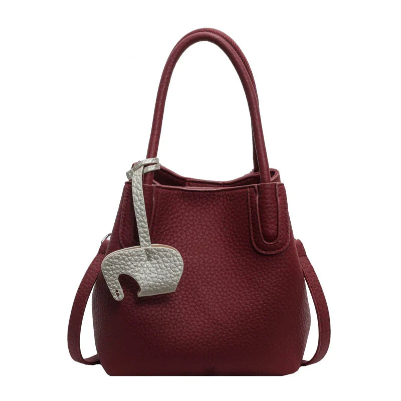 Borsa a mano in pelle rossa con ciondolo a forma di elefante, design elegante, manici doppi, ideale per moda donna e accessori di lusso.