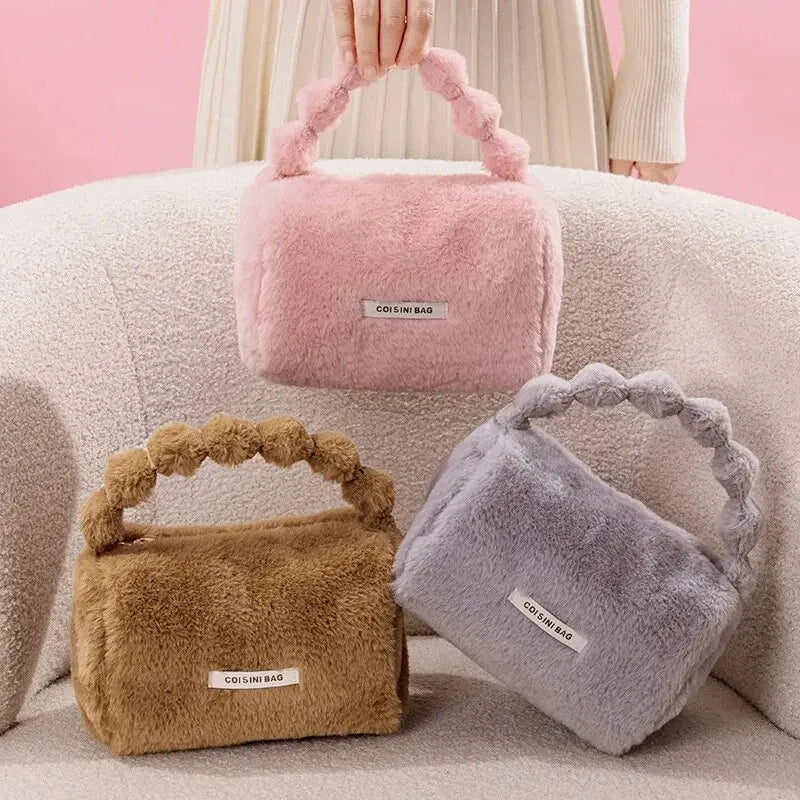 Tre borse in pelliccia sintetica colorate, rosa, marrone e grigio, con manico intrecciato, su sfondo rosa. Eleganti accessori moda invernali.