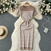 Abito a righe beige e bianche su tappeto peloso bianco, circondato da rose bianche e accessori moda. Elegante, casual, perfetto per l'estate.