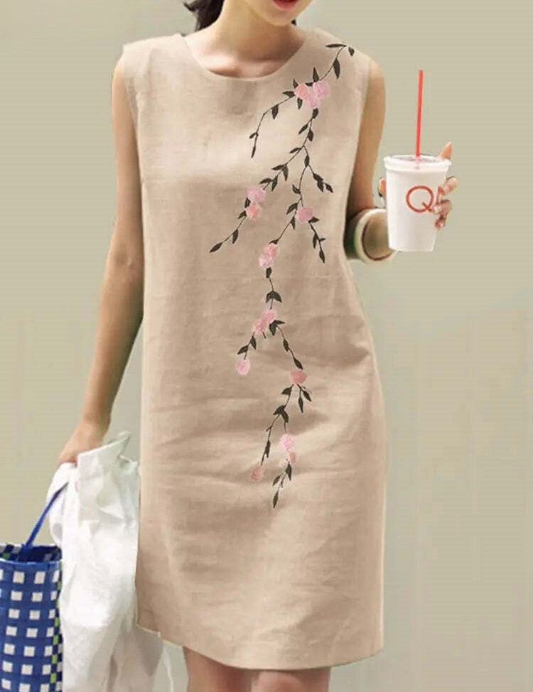 Abito estivo beige senza maniche con stampa floreale rosa, donna con bicchiere di bevanda e borsa a rete blu. Moda casual elegante.