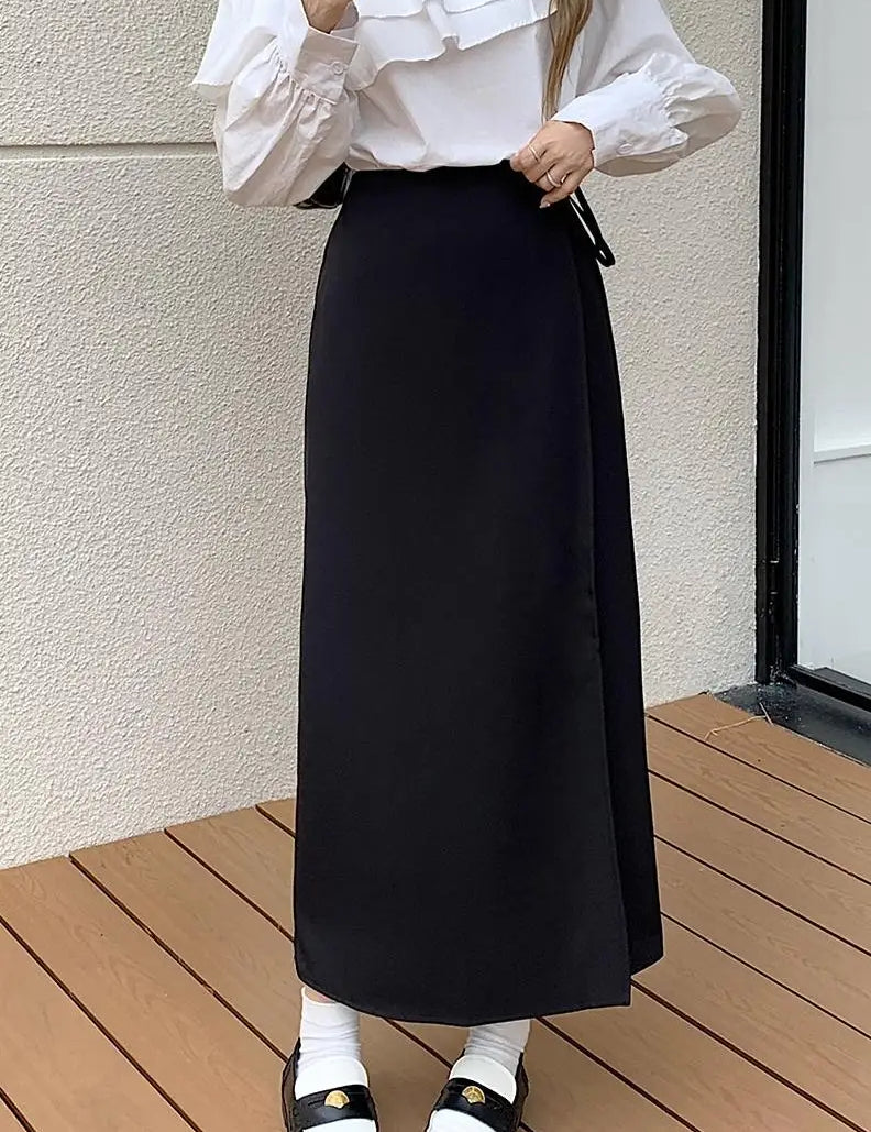 Donna con camicia bianca a volant e gonna lunga nera, scarpe nere con calzini bianchi. Moda elegante, abbigliamento femminile autunnale.