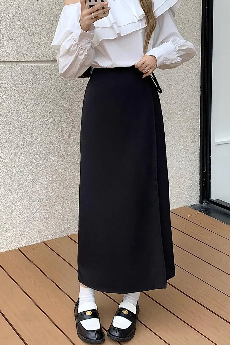Donna con camicia bianca a volant e gonna lunga nera, scarpe nere con calzini bianchi. Moda elegante, abbigliamento femminile autunnale.
