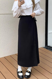 Donna con camicia bianca a volant e gonna lunga nera, scarpe nere con calzini bianchi. Moda elegante, abbigliamento femminile autunnale.