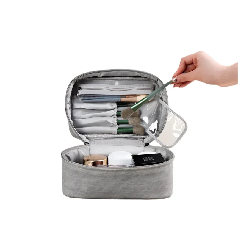 Astuccio da trucco grigio aperto con pennelli, cosmetici e scomparti organizzati. Ideale per viaggi, accessori make-up, beauty case compatto.