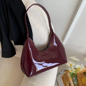 Borsa a spalla in pelle lucida bordeaux, design elegante e moderno, perfetta per moda donna. Accessorio chic per ogni occasione.