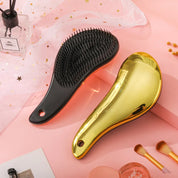 Spazzole per capelli districanti, una nera e una dorata, su sfondo rosa con accessori di bellezza. Design ergonomico, setole morbide.