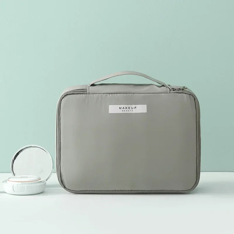 Borsa trucco grigia con manico, design elegante e compatto, ideale per organizzare cosmetici. Perfetta per viaggi e uso quotidiano.