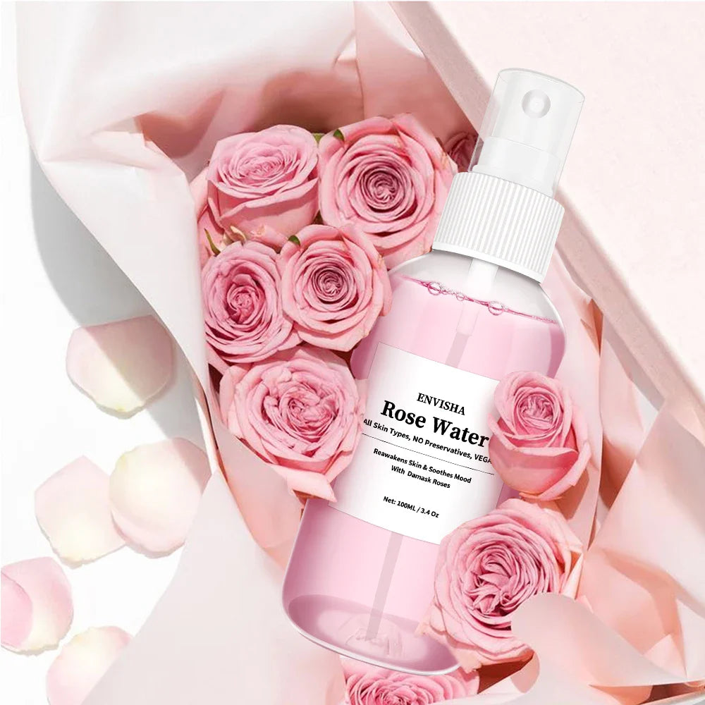 Spray acqua di rose Envisha 100ml, flacone bianco con etichetta rosa, circondato da rose rosa e petali, ideale per cura della pelle e idratazione.