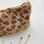 Borsa trucco floreale beige con fiori arancioni, accessori cosmetici inclusi. Design elegante, ideale per organizzare trucchi e accessori di bellezza.