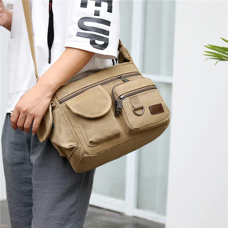 Borsa a tracolla uomo in tela beige, multi-tasche, stile casual, ideale per viaggi e lavoro. Design pratico e resistente.