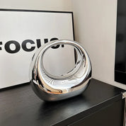 Scultura moderna in metallo cromato su mobile nero, design astratto, decorazione d'interni elegante, riflessi lucidi, arte contemporanea.