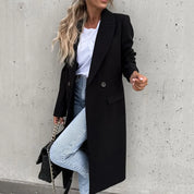 Donna con cappotto nero elegante, jeans chiari e borsa a catena. Moda autunnale, stile casual chic. Sfondo grigio minimalista.