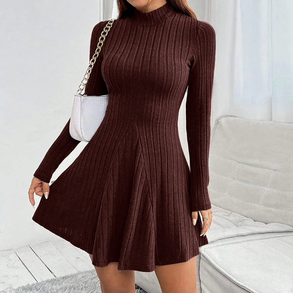Vestito maglione marrone a coste, maniche lunghe, scollo alto, abbinato a borsa bianca a tracolla. Elegante abbigliamento autunnale da donna.