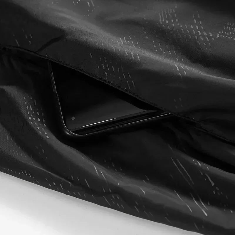 Smartphone nero in tasca di giacca impermeabile nera, design elegante e moderno, accessorio tecnologico, moda outdoor, protezione dispositivo.