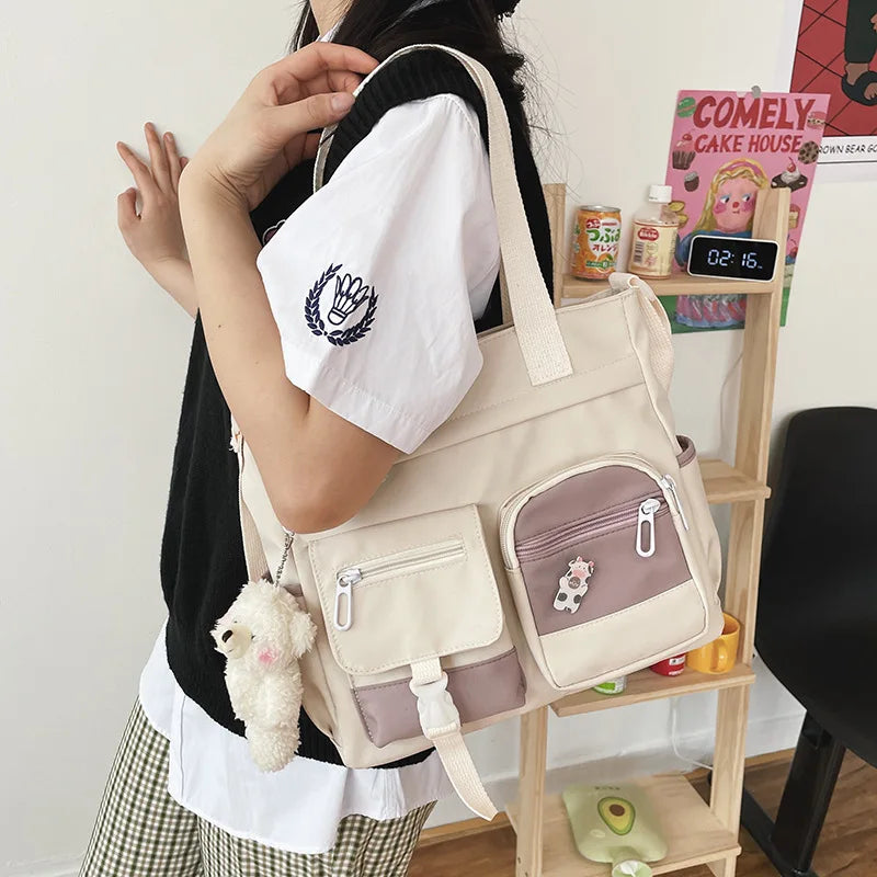 Zaino beige e rosa con tasche multiple, decorato con portachiavi a forma di orsetto. Perfetto per scuola o lavoro, stile casual e funzionale.