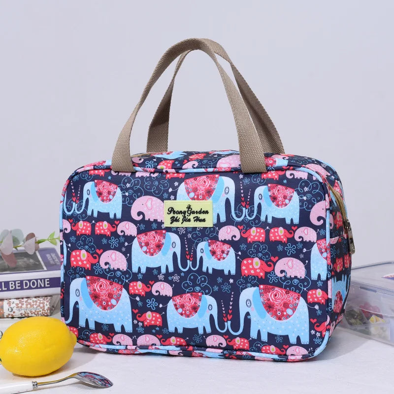 Borsa termica con stampa elefanti colorati, manici beige, su tavolo con limone e libro. Ideale per picnic e pranzo al sacco.