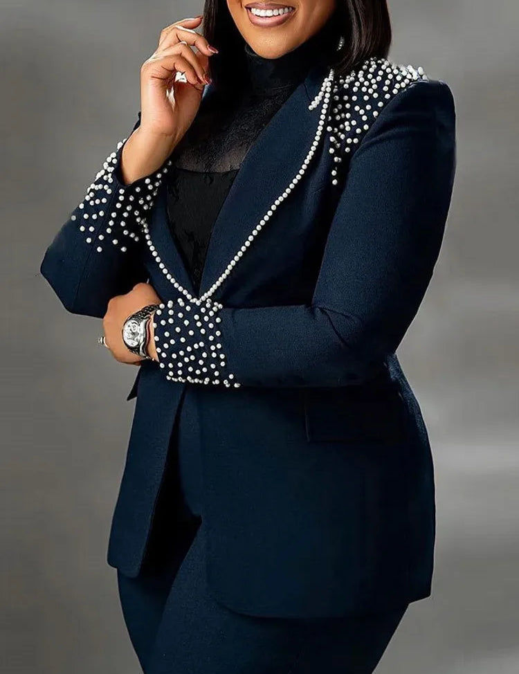 Giacca elegante blu scuro con perle decorative su spalle e polsini, indossata da donna. Moda formale, abbigliamento da ufficio, stile sofisticato.