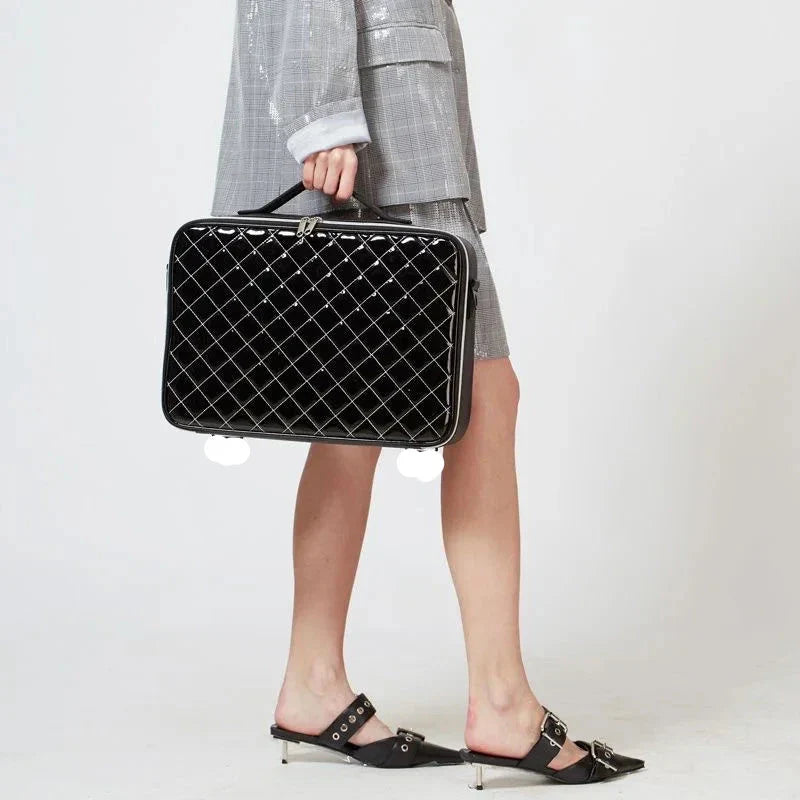 Donna con valigetta nera trapuntata, abito grigio elegante, scarpe con tacco basso. Accessorio moda, stile business chic.