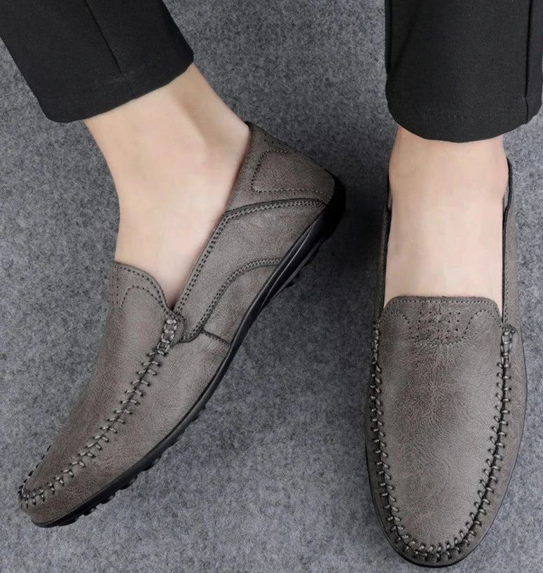 Scarpe mocassini da uomo in pelle grigia, design elegante e cuciture dettagliate, ideali per look casual e formali. Comfort e stile garantiti.