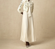 Abito lungo bianco elegante con giacca ricamata, maniche a tre quarti, gonna plissettata, scarpe con tacco. Moda femminile sofisticata.