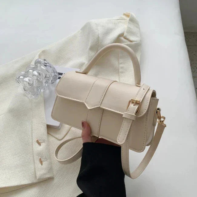 Borsa a tracolla beige elegante su sfondo bianco, design minimalista, chiusura a fibbia dorata, perfetta per moda femminile e accessori di tendenza.