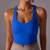 Donna indossa top sportivo blu, senza maniche, con scollo a U, ideale per yoga e fitness. Tessuto traspirante, design moderno ed elegante.