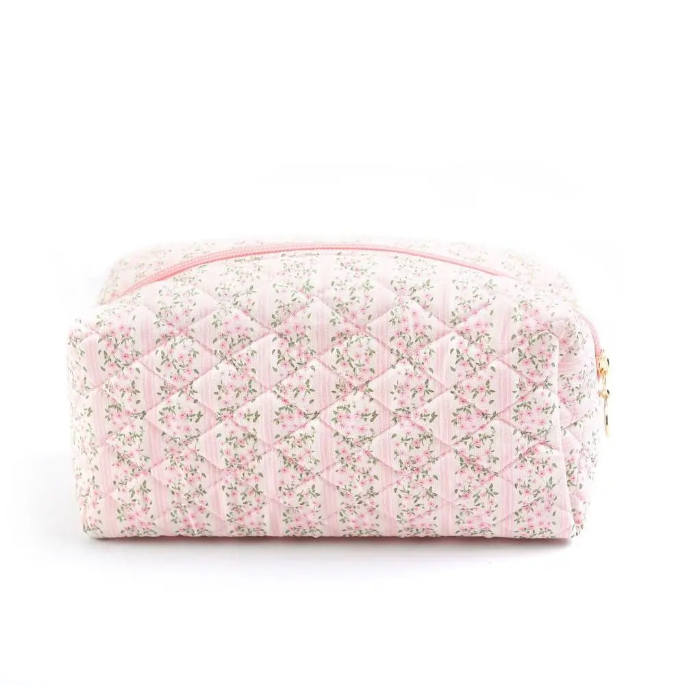 Astuccio da toilette trapuntato rosa con motivo floreale, cerniera dorata. Accessorio elegante per cosmetici, ideale per viaggi e organizzazione.