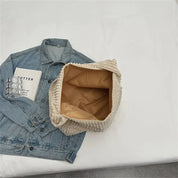 Giacca di jeans blu con libro e cartone di uova su tavolo bianco, accanto a borsa beige aperta. Accessori moda casual, stile urbano.