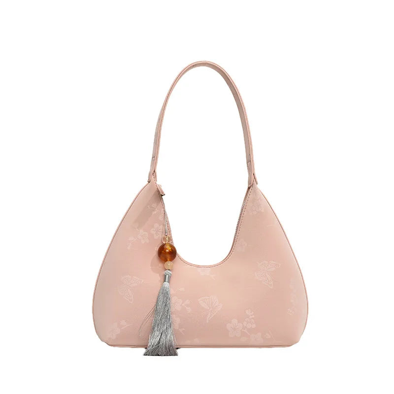 Borsa a spalla rosa chiaro con motivo floreale, decorata con nappina grigia e perla marrone. Elegante accessorio moda donna.