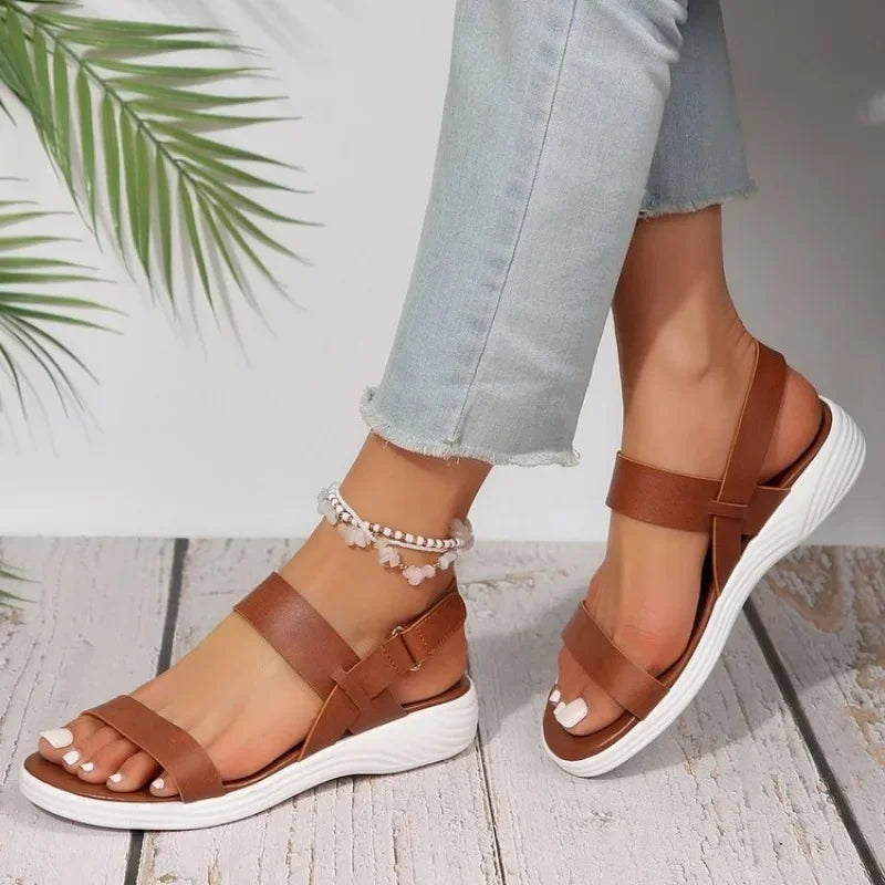 Sandali donna in pelle marrone con suola bianca, indossati con jeans chiari. Design casual estivo, perfetti per moda estiva e comfort quotidiano.