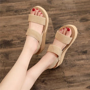 Sandali beige con zeppa, doppia fascia in tessuto, su pavimento in legno. Scarpe estive donna, comode e alla moda, ideali per passeggiate.