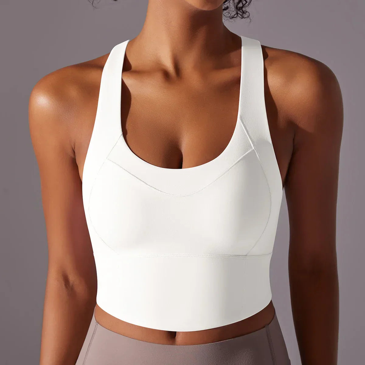 Top sportivo bianco da donna, senza maniche, con scollo a U, indossato su sfondo grigio. Ideale per yoga, fitness e allenamento.