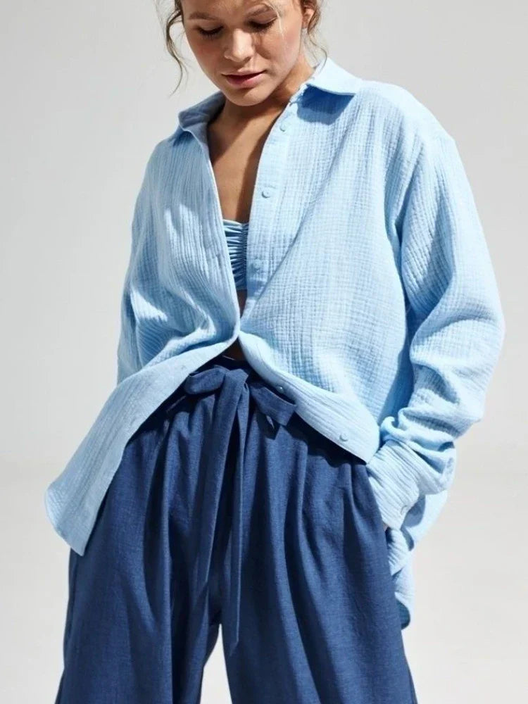 Donna con camicia azzurra in cotone leggero e pantaloni blu a vita alta. Moda casual estiva, abbigliamento femminile elegante e confortevole.