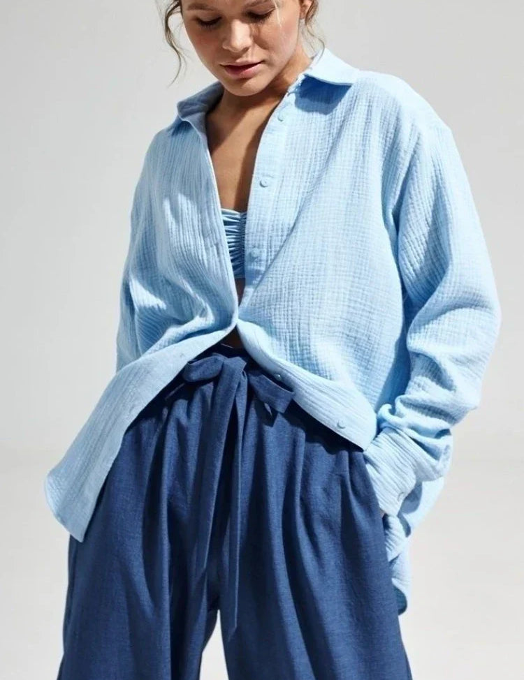 Donna con camicia azzurra in cotone leggero e pantaloni blu a vita alta. Moda casual estiva, abbigliamento femminile elegante e confortevole.