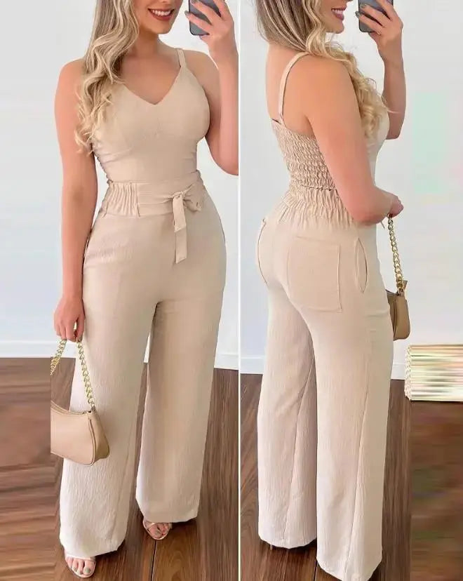 Donna in tuta beige elegante con cintura, pantaloni a gamba larga, sandali e borsa a tracolla. Moda femminile estiva, abbigliamento casual chic.