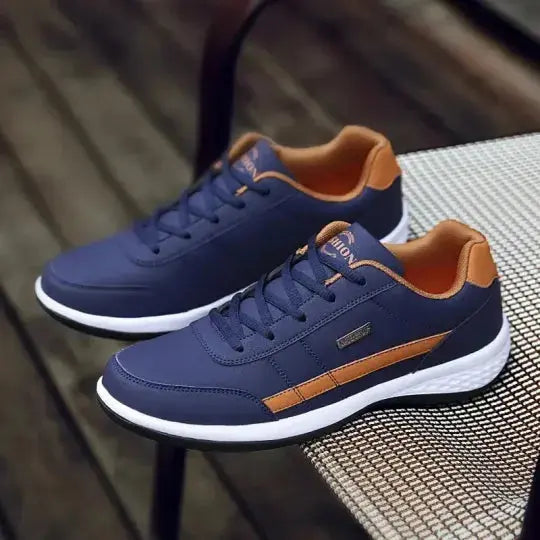 Scarpe da ginnastica blu e arancioni su sedia, design moderno, suola bianca, perfette per sport e tempo libero. Scarpe uomo casual eleganti.