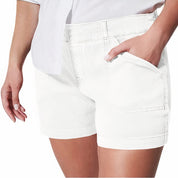 Donna indossa shorts bianchi in denim, tasche frontali, abbinati a camicia bianca. Moda estiva casual, abbigliamento femminile trendy.