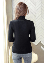 Maglione nero a collo alto da donna, visto da dietro, abbinato a jeans grigi. Design elegante e moderno, perfetto per l'autunno e l'inverno.