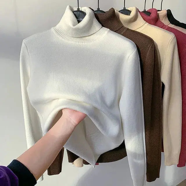 Maglione dolcevita bianco in lana, esposto su appendiabiti con vari colori. Moda autunno inverno, abbigliamento caldo e confortevole.
