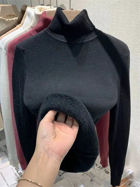 Maglione nero a collo alto in lana, esposto su appendiabiti con altri colori. Moda invernale, abbigliamento caldo e confortevole.