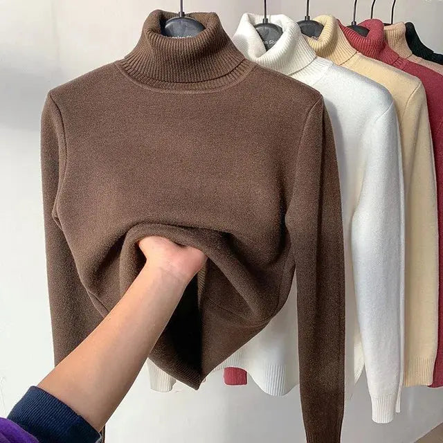 Maglioni a collo alto in vari colori su appendiabiti, con mano che tocca il maglione marrone. Tessuto morbido, moda autunno inverno, abbigliamento casual.