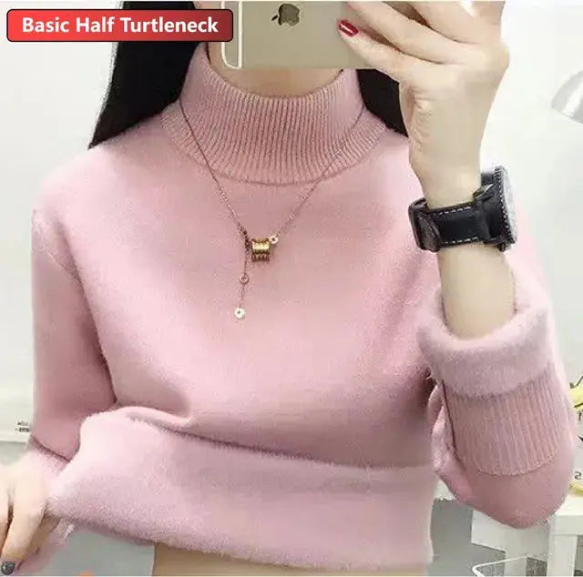 Maglione rosa a collo alto, maniche lunghe, indossato da una donna. Accessori: orologio nero e collana. Stile casual elegante.