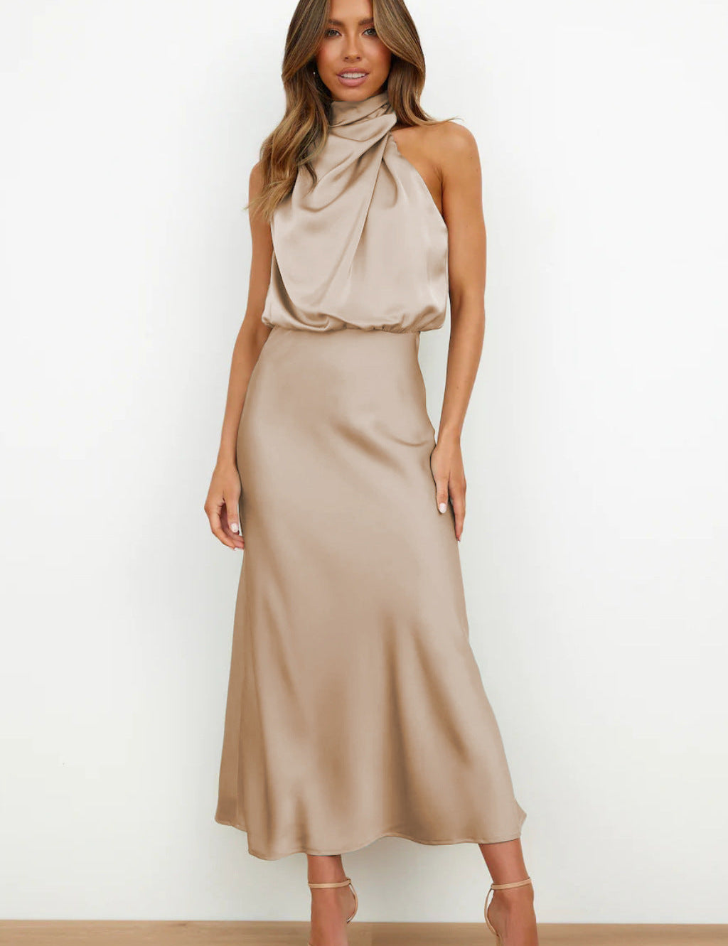 Abito lungo elegante in raso beige, senza maniche, con scollo drappeggiato. Perfetto per eventi formali e serate speciali.