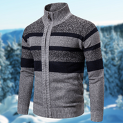 Maglione invernale da uomo grigio con zip, collo alto e righe blu scuro, sfondo innevato. Maglieria calda e alla moda per l'inverno.