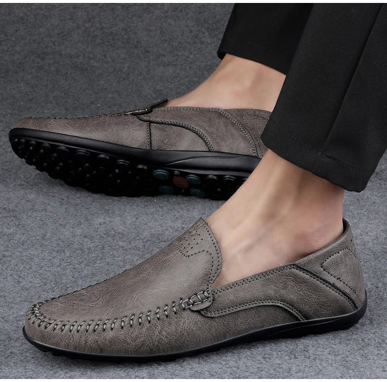 Scarpe mocassino uomo in pelle grigia, suola antiscivolo, design elegante e casual, ideali per abbigliamento formale e quotidiano.