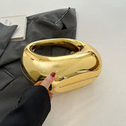Borsa a mano dorata lucida su sfondo grigio, design moderno e elegante, accessorio moda femminile, perfetta per eventi e serate glamour.