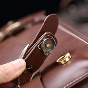 Borsa in pelle marrone con chiusura magnetica, dettaglio del fermaglio in metallo dorato. Accessorio moda elegante e funzionale.
