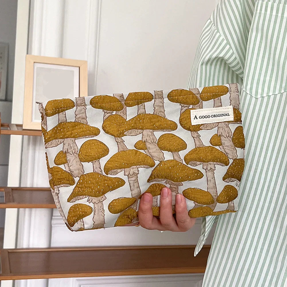 Borsa a mano con stampa di funghi gialli, design originale, tenuta da una persona in camicia a righe verdi. Accessorio moda unico e trendy.