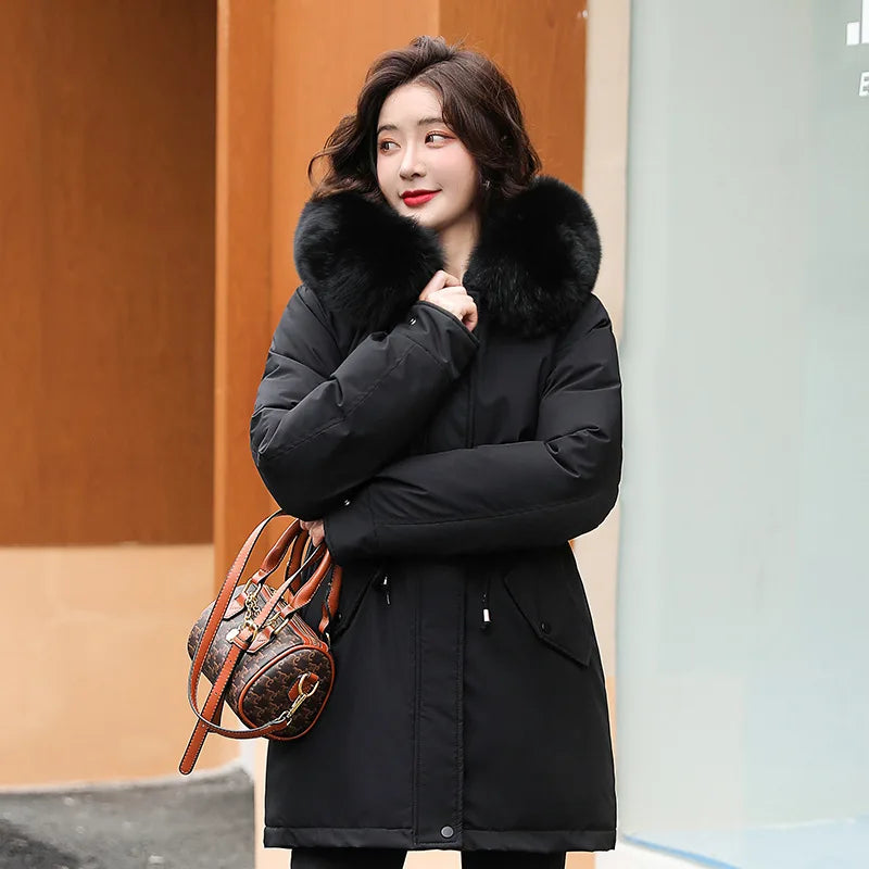 Donna con cappotto invernale nero con collo in pelliccia, borsa a tracolla marrone. Moda invernale elegante, abbigliamento caldo per donne.